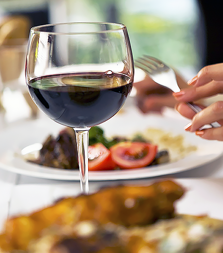 Woman eating dinner with a glass of wine